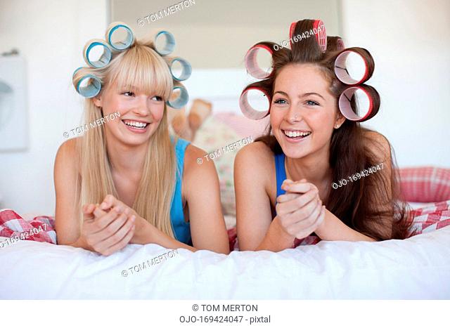 Women laying on bed with curlers in hair