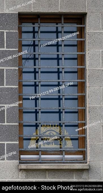 11 December 2023, Saxony, Dresden: A candle arch with the logo of the third division soccer team SG Dynamo Dresden can be seen behind the bars at the window of...