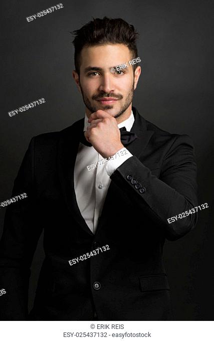 Portrait of a beautiful latin man with tuxedo and holding a clapboard