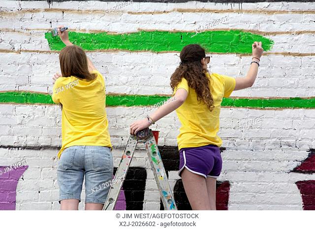 Detroit, Michigan - High school volunteers paint a mural on the wall of the Detroit Nipple Works, a manufacturer of pipefitting supplies
