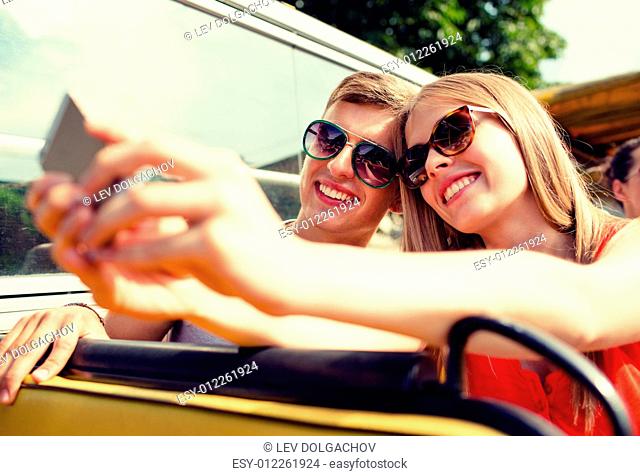 travel, vacation, technology, summer and people concept - smiling couple with smartphone traveling by tour bus and making selfie