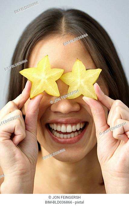 Asian woman holding star fruits over eyes
