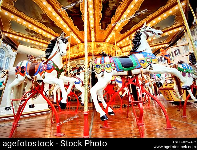 white painted horses in a carousel decorated with lights and gold. Street party and fun