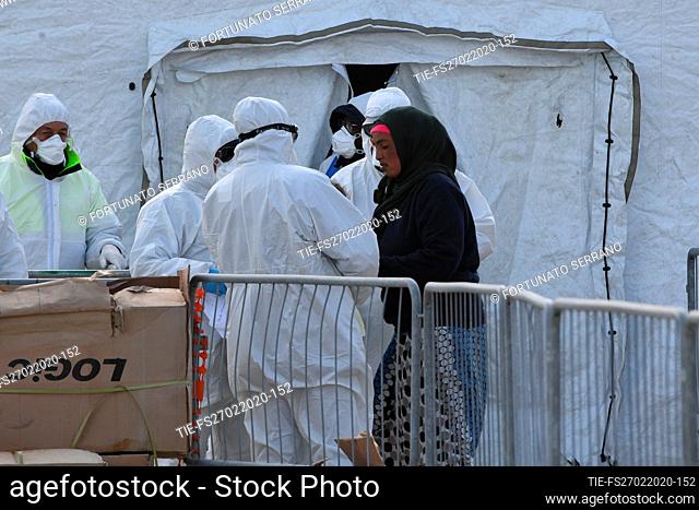 Italian officials wearing protective suits check migrants disembarking from the NGO ship Sea Watch 3 at the port in Messina
