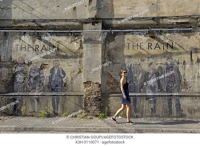 young woman walking in front a wall, with a graffiti from the Danish TV series ''The Rain'', within Tytano, Urban Lifestyle Complex installed in a former...