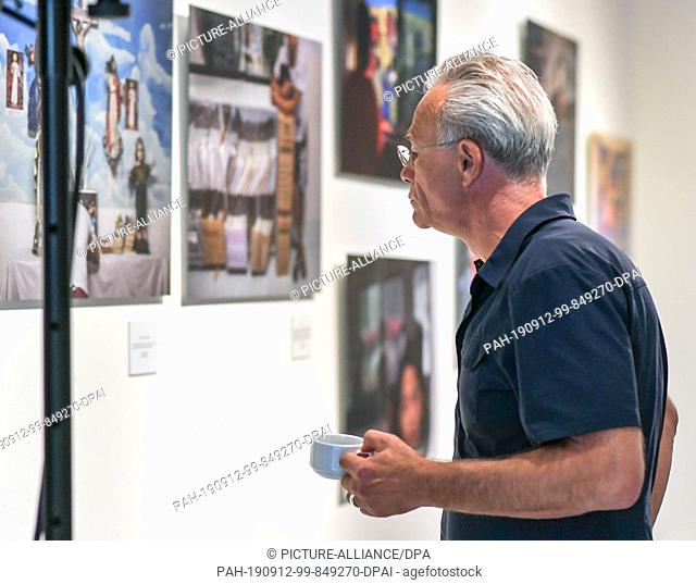 11 September 2019, Berlin: The crime scene actor Klaus J. Behrendt looks at the pictures in the photo exhibition ""Children behind bars"" in the Mensing Gallery