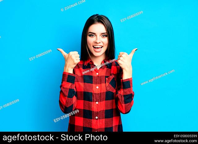Happy smiling hipster woman showing thumbs up on blue background. Motivation, ok, success concept