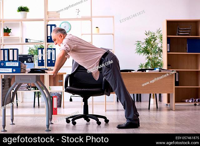 Senior male employee doing physical exercises at workplace