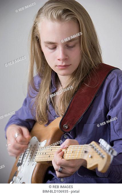 Caucasian teenage boy playing guitar