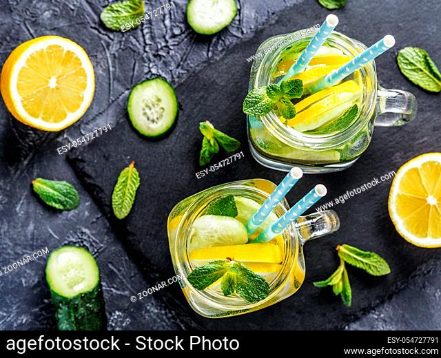 Above view of two mason jar with detox water on dark concrete background. Summer drink with cucumber, lemon and mint. Copy space. Top view or flat lay