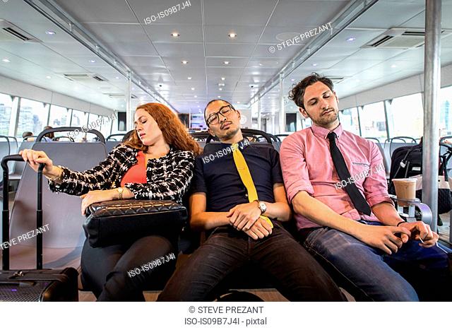 Businesswoman and men asleep on passenger ferry