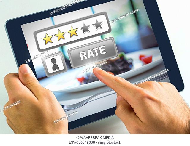 Hand touching tablet with Rate button and review stars in restaurant with dinner food