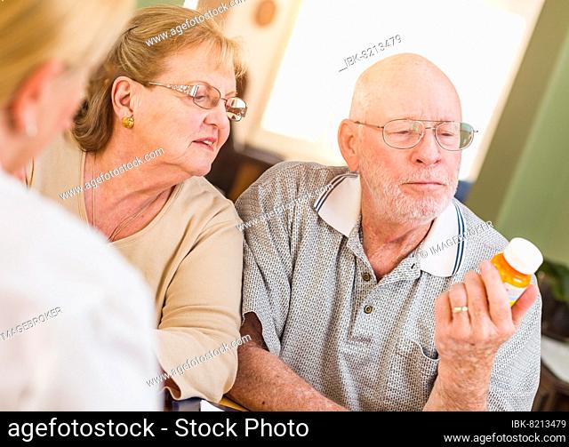 Doctor or nurse explaining prescription medicine to senior adult couple