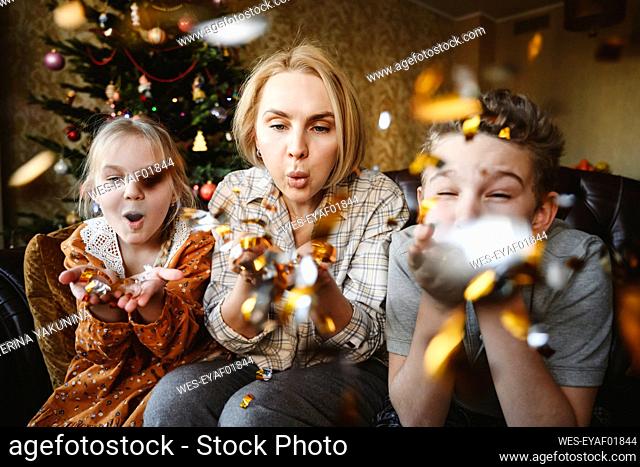 Mother with daughter and son blowing confetti at home