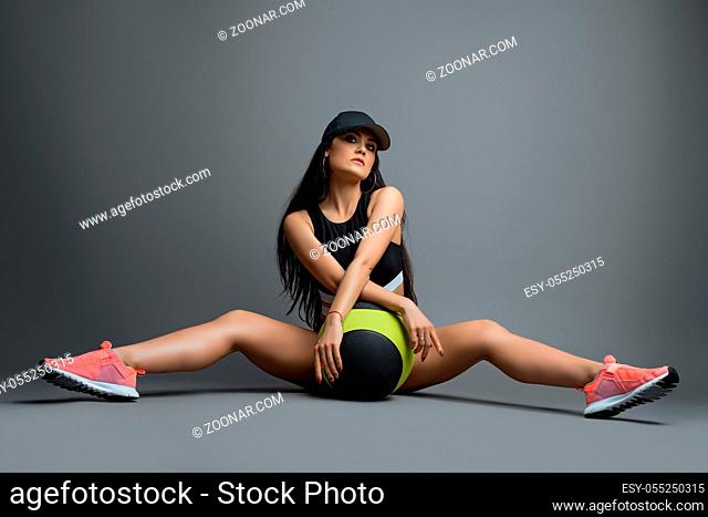 Beautiful brunette in sexy sportswear sitting on the floor with a ball between her slim legs shot