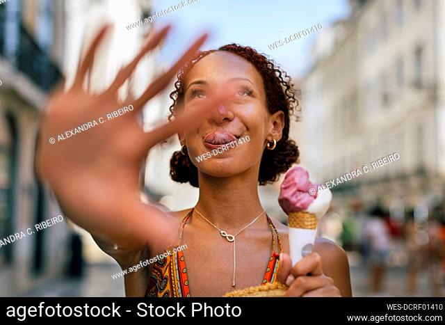 Young woman holding ice cream gesturing stop sign