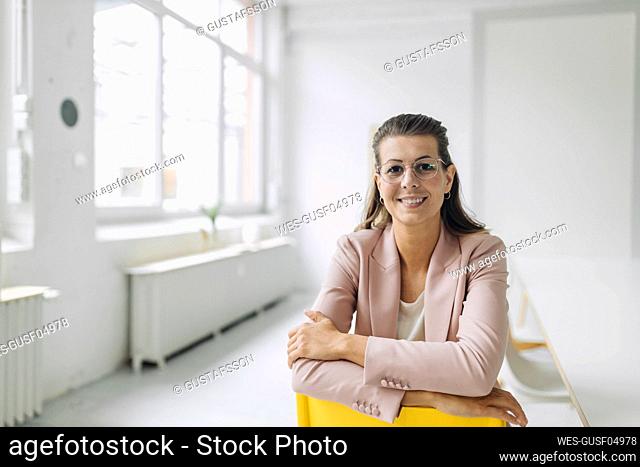 Portrait of smiling businesswoman sitting on chair in empty office