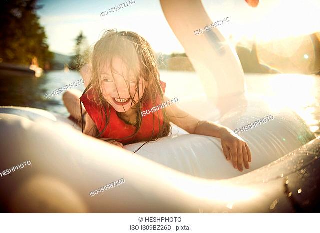 Girl playing on inflatable swan in lake