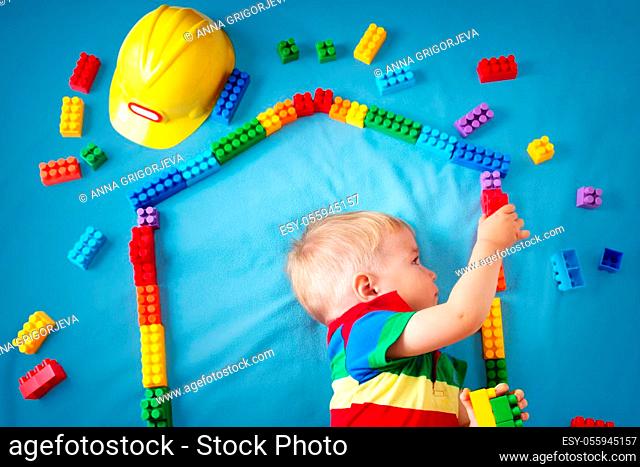 Child lying on blue blanket with blocks in house shape