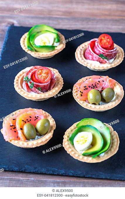 Tartlets with different fillings on the stone board