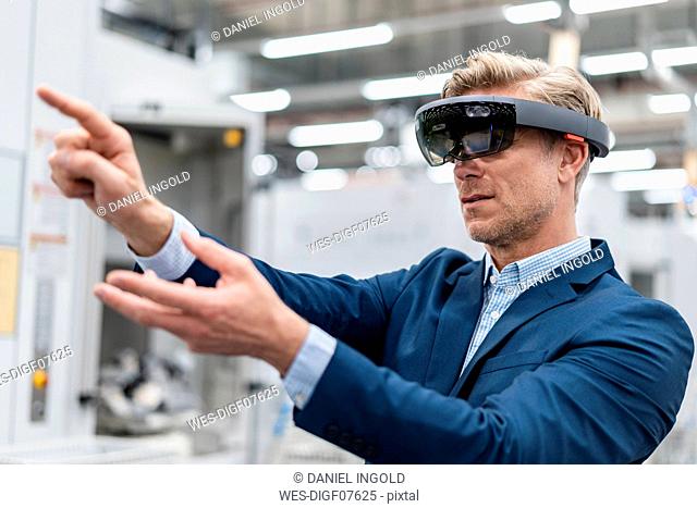 Businessman wearing AR glasses in a modern factory
