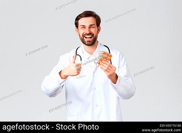 Hospital, healthcare workers, covid-19 treatment concept. Happy cheerful caucasian doctor smiling, show thumb-up in approval and advice medication