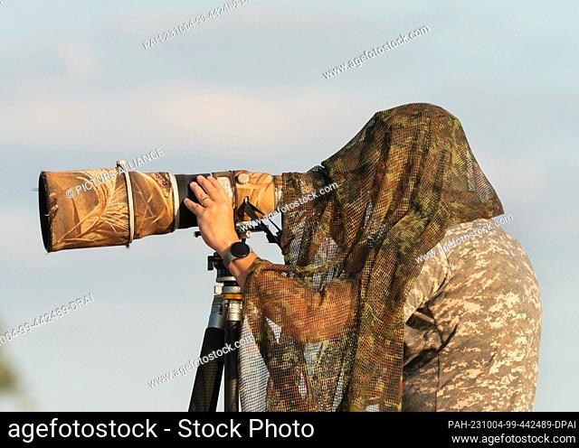 25 September 2023, Saxony-Anhalt, Lutherstadt Wittenberg: 28.09.2023. A nature photographer is standing on a dike at the Elbe meadows on the Elbe