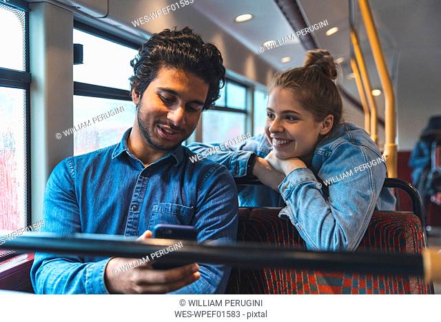 Young couple travelling by bus on rainy day, London, UK