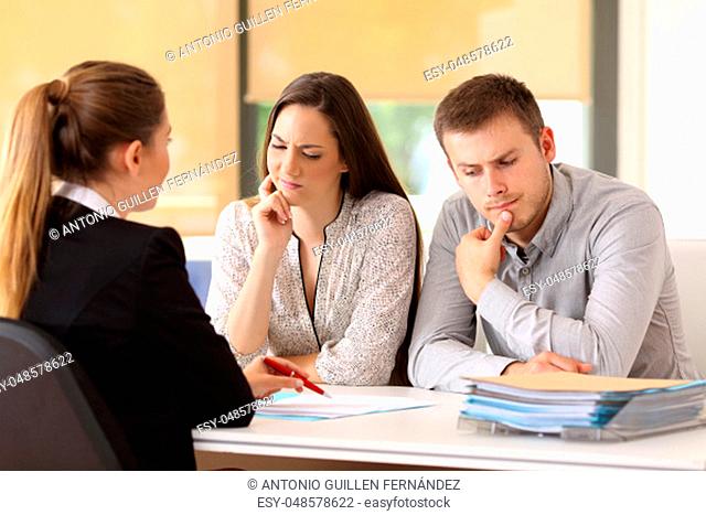 Office worker attending and showing contract trying to convince to a suspicious couple sitting in a desk at office