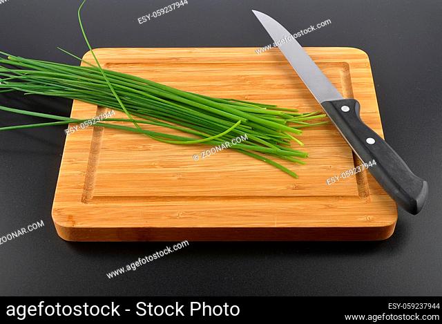 Schnittlauch mit Messer auf Schneidbrett - Chives with table knife and cutting board on black