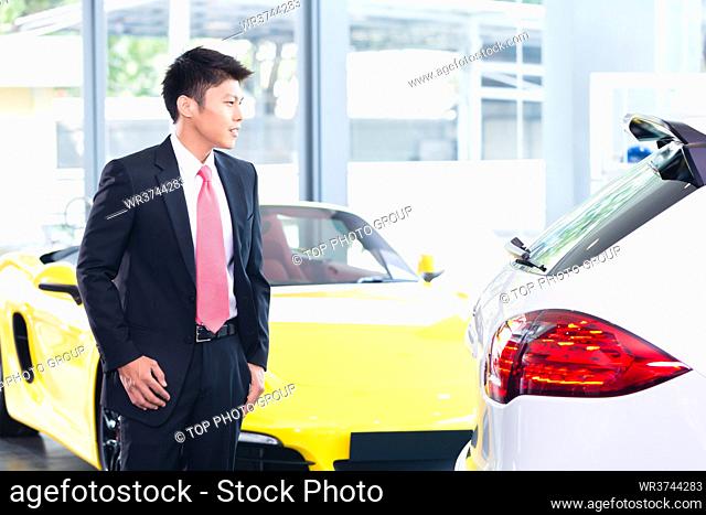 Chinese man buying luxury car in dealership