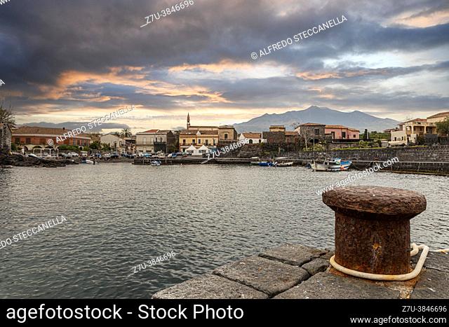 View of a small Sicilian fishing port. In the background stands the Etna volcano