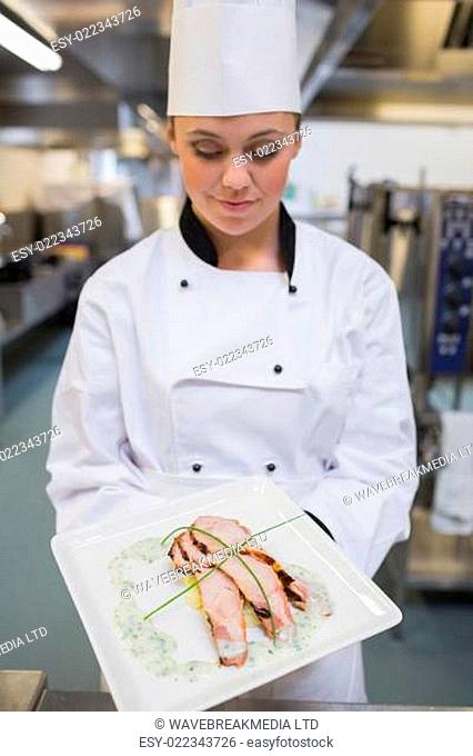 Smiling chef looking down at her plate in the kitchen