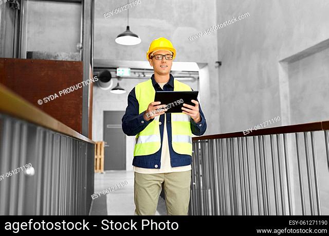 worker in helmet and safety west with tablet pc