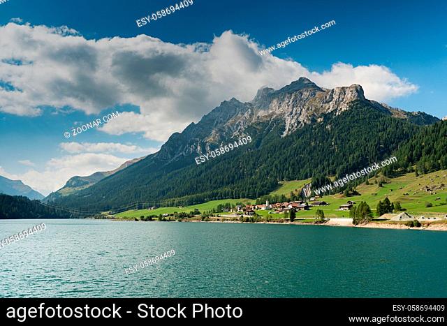view of an idyllic and picturesque turquoise mountain lake surrounded by green forest and mountain peaks in the Swiss Alps near Sufers