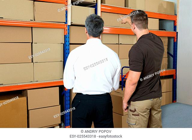 Manager With Clipboard Showing Something To His Worker In Warehouse