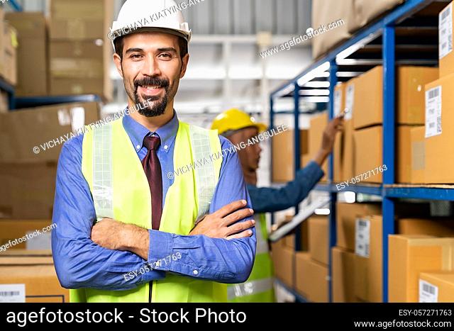 Portrait of Middle east Turkish White caucasian warehouse manager crossed arm with his worker working in background in warehouse distribution center environment