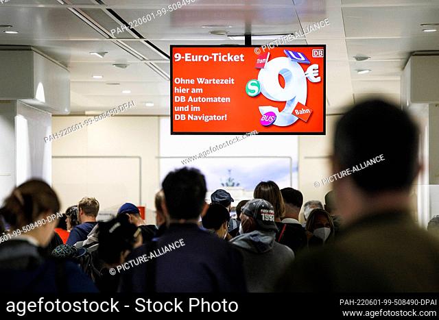 01 June 2022, Berlin: Customers stand in line under a sign for the 9-euro ticket at the Deutsche Bahn travel center in Berlin's main train station
