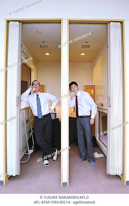 Businessmen standing in capsule hotel