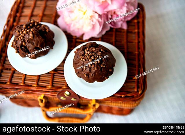 Chocolate muffins and beautiful pink peonies lie on a wooden suitcase. Beautiful composition