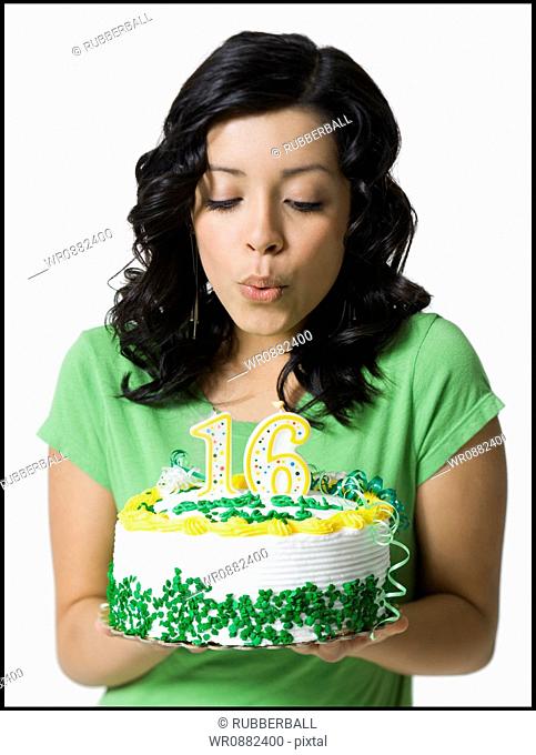 Close-up of a teenage girl blowing out candles on her birthday cake