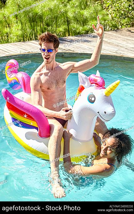 Happy young couple with inflatable in swimming pool