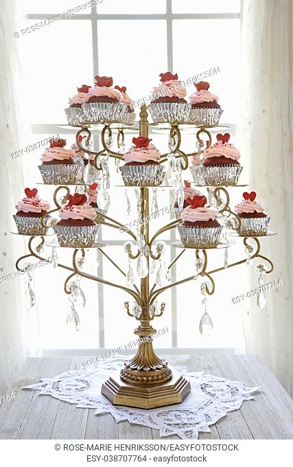 Red velvet cupcakes displayed on a chandelier in front of a window