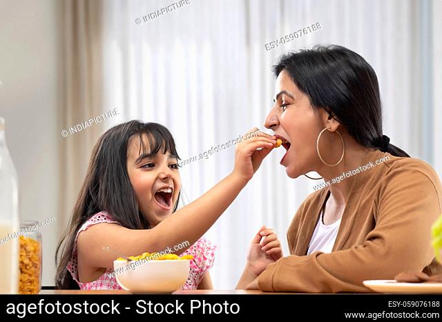 A YOUNG GIRL HAPPILY GIVING NAMKEEN TO MOTHER