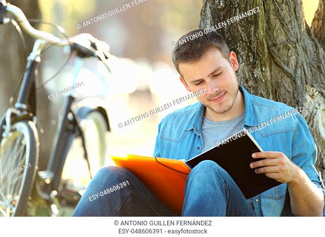 Single student studying reading notes outdoors sitting in a park