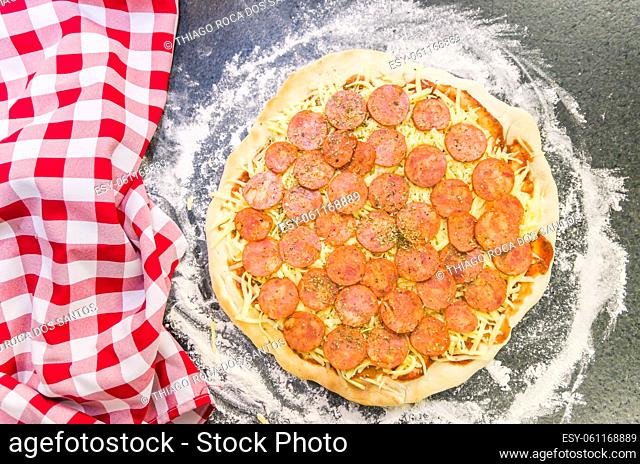 Preparing pepperoni pizza on black granite table