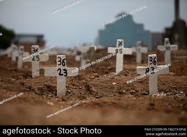 06 March 2021, Brazil, Rio De Janeiro: Simple crosses with numbers stand at graves in the Iraja cemetery, north of the city