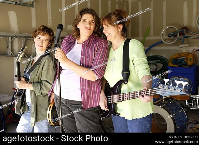 Portrait of Garage band composed of middle aged women with instruments, practicing in residential garage