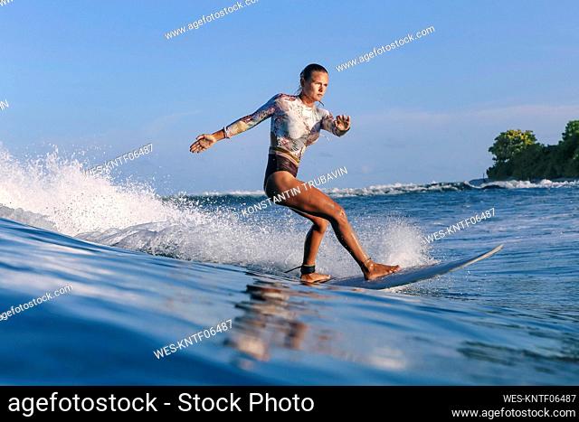 Woman in swimsuit surfing on board during vacation