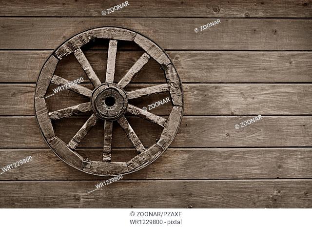 Old wagon wheel on wooden wall